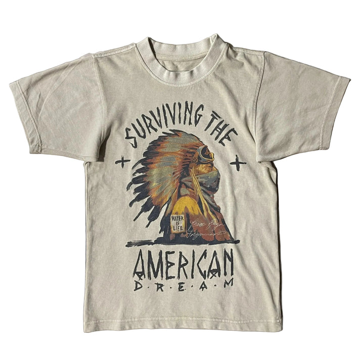 T-shirt with Native American graphic design with the words "surviving the American Dream" on a white background