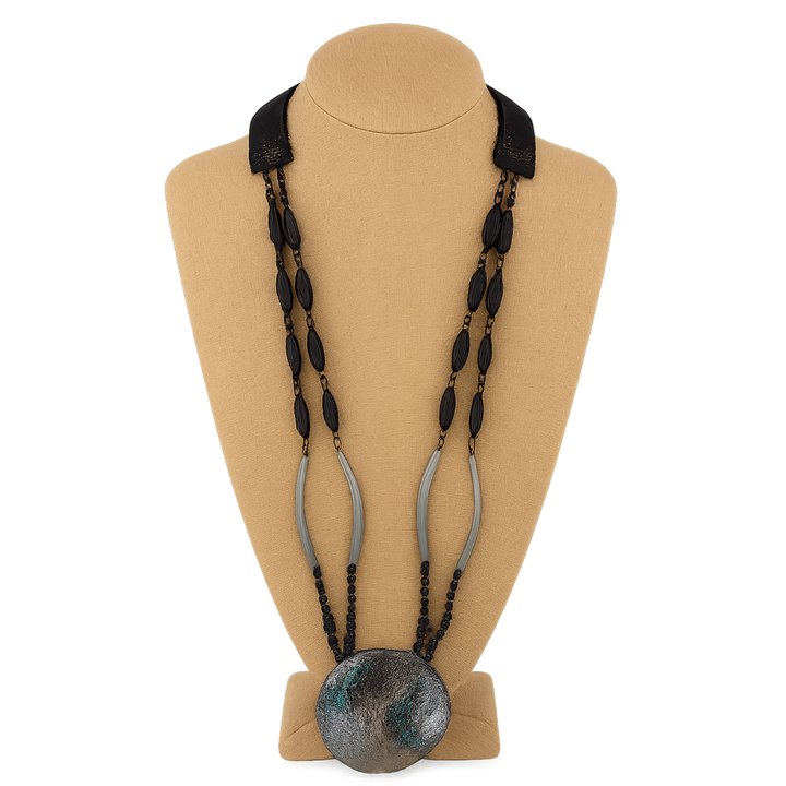 Necklace with black beads and a large round pendant on a beige mannequin bust.