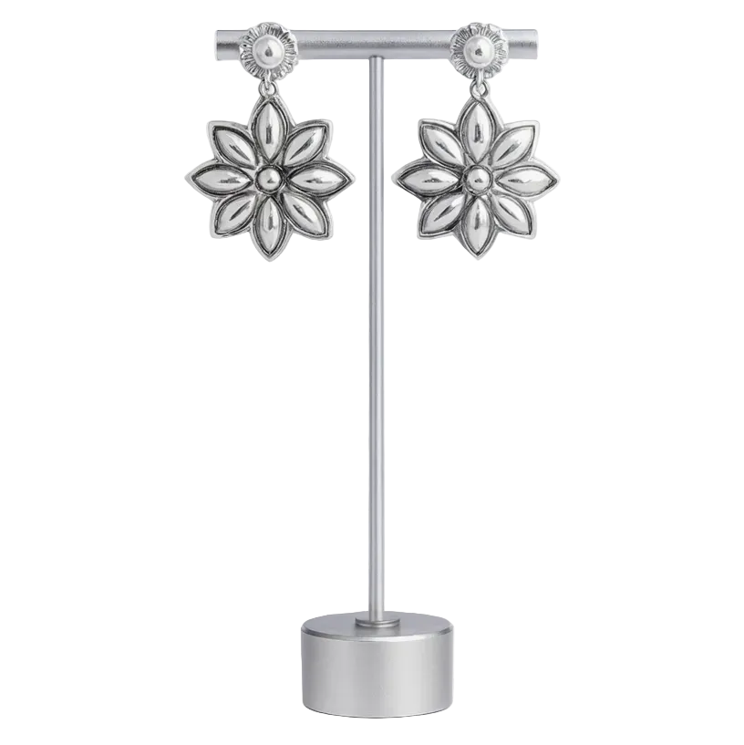 Flower-shaped silver earrings on a stand against a white background