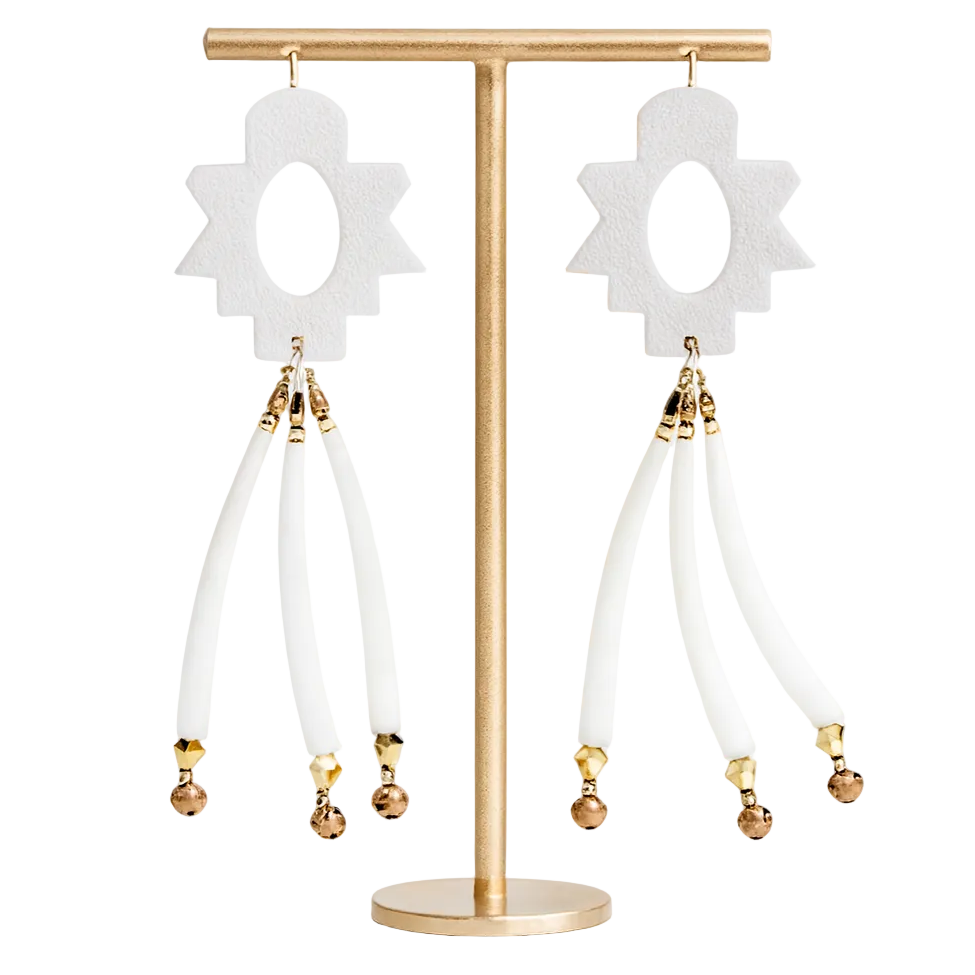 Pair of earrings with white flower-like tops and gold beads on a gold stand against a white background