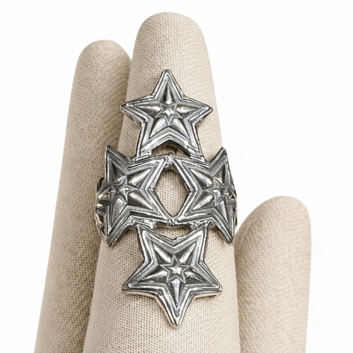 Silver star-shaped ring on a beige glove with a white background